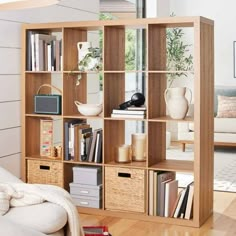 a living room filled with furniture and bookshelves next to a white couch on top of a hard wood floor