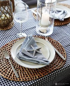 a place setting with napkins and silverware on a wicker tablecloth covered table