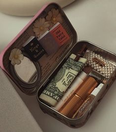 an open tin box filled with lots of different items on top of a white table