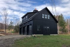 a large black barn sitting on top of a lush green field