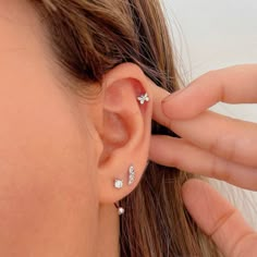 a close up of a person's ear with three small diamond studs