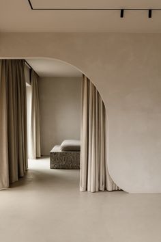 an arch in the middle of a room with drapes on both sides and a bed behind it