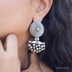 The Niovi Abheer Silver Earrings with an oxidised finish showcase a captivating blend of intricate design and vintage allure. The darkened patina enhances their detailed craftsmanship, offering a unique and elegant statement piece that complements both traditional and modern styles. Silver Jhumkas, India Inspired, Tarnished Silver, Intricate Design, Earring Necklace, Indian Jewelry, Shop Earrings, Silver Earrings, Patina