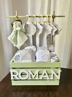 a wooden crate filled with baby clothes on top of a table next to a curtain