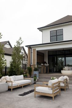 an outdoor living area with couches and chairs in front of a large white house