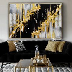 a living room with black couches, gold pillows and a large painting on the wall