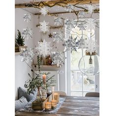 a dining room table with snowflakes hanging from the ceiling and candles on it