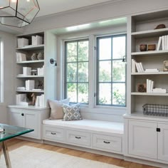 a window seat in the corner of a room with bookshelves and drawers on either side