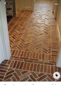 an empty hallway with brick flooring and white trim on the walls, leading to another room