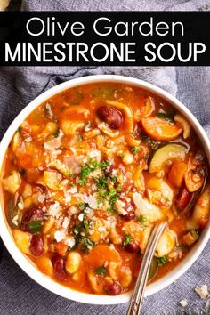 A bowl of minestrone soup filled with a mix of vegetables, beans, pasta, and herbs, topped with grated cheese. A spoon is resting inside the bowl, and its placed on a dark fabric surface. Minestrone Soup Recipe Olive Garden, Copycat Olive Garden Minestrone Soup, Copycat Olive Garden Minestrone, Olive Garden Minestrone, Olive Garden Soup, Olive Garden Minestrone Soup, Copycat Olive Garden, Minestrone Soup Recipe, Hearty Meal