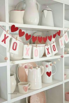 valentine's day decorations are displayed on shelves in the kitchen, including mugs and teapots