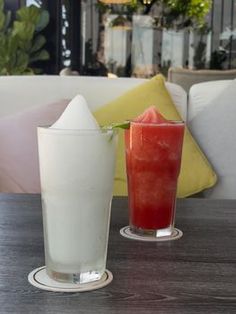 two drinks sitting on top of a wooden table next to each other in front of a couch