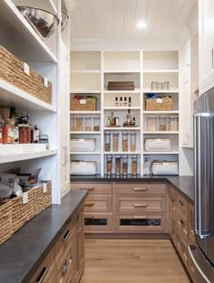 an organized pantry with lots of shelves and baskets on the counter top, along with two refrigerators