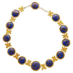 Lapis Necklace in 14k & 18K Gold. This Riviera styled necklace features 12 cabochon-cut lapis gemstones, each measuring 19–16 mm, and exhibits gold detailing within each stone, enhancing the royal blue hue. The necklace is crafted from 14K & 18K yellow gold, and surround each lapis stone with a textured design. The gold is also crafted into paisley art nouvea design between each stone, adding a feel of historical elegance to the piece. Comfortably sized at 17 inches and weighing 71.02 grams, this substantial chain necklace is a perfect gift to add to your jewelry collection. Item Details: - Type: Necklace - Metal: 14K Yellow Gold, 18K Yellow Gold - Weight: 71.02 grams - Setting: Bezel - Size: 17 inches _______________________ Stone Details: - Lapis: 12 Cabochon cut Lapis, 19-16mm (each) __ Motifs Art Nouveau, Lapis Stone, Lapis Necklace, Paisley Art, Textured Design, Metal Necklaces, Blue Hues, Gold Details, Art Nouveau