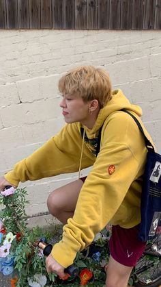 a person on a bike with flowers in the front basket and wearing a yellow hoodie