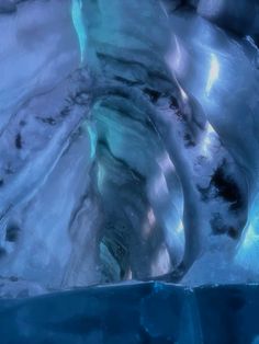 an ice cave with water flowing down it's sides and lights shining on the walls