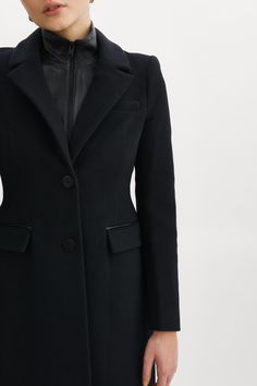 The Malva wool coat marries the best of polished glamour and feminine flair. The structured wool offers refined texture, while the semi-fitted hourglass silhouette offers a flattering fit. Elegant extras — like a removable leather bib, notched collar and flap pockets — also play a starring role. Shoulder pads add structure and the single-breasted, button-down design conveys timelessness. Black Removable inner leather dickie with zipper Single breasted button closure Notched collar Shoulder pads Elegant Tailored Wool Coat For Winter, Elegant Long Wool Coat With Concealed Placket, Elegant Tailored Long Wool Coat, Elegant Long Wool Coat With Hidden Buttons, Chic Fitted Single Breasted Wool Coat, Chic Fitted Wool Coat For Formal Occasions, Chic Structured Outerwear With Pressed Crease, Elegant Fitted Long Wool Coat, Chic Fitted Single-breasted Wool Coat