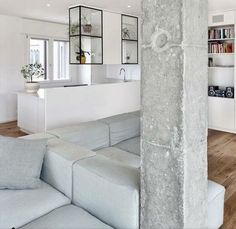 a living room filled with furniture next to a white wall and wooden flooring covered in bookshelves