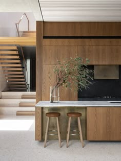 a kitchen with two stools next to a sink and counter top in front of stairs