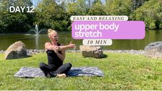 a woman sitting on top of a yoga mat in front of a pond and holding her hands out