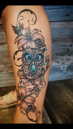 a woman's leg with an owl and flower tattoo design on the side of her thigh