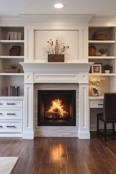 a living room with a fire place in the center and white bookcases on either side