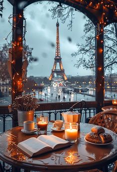 an open book on a table with candles in front of the eiffel tower