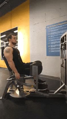 a man sitting on top of a machine in a gym