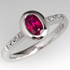 This lovely ring is centered with one (1) oval cut natural ruby set into a bezel setting. The top face of the shank is accented with a row of four (4), prong set, round brilliant cut diamonds on each side. The ring measures 8.6mm at the top, rises 5.0mm above the finger, tapering to 2.3mm wide and 1.5mm thick at the base of the shank. This ring is currently a size 6.5. Timeless Oval Ruby Ring With Diamonds, Elegant Ruby Ring With Oval Diamond, Formal Ruby Ring With Oval Cabochon Center Stone, Formal Ruby Ring With Oval Cabochon, Formal Oval Ruby Ring With Center Stone, Lab-created Ruby Ring With Brilliant Cut In Oval Shape, Formal Red Sapphire Ring With Oval Shape, Formal Red Oval Sapphire Ring, Elegant Oval Ruby Ring With Bezel Setting