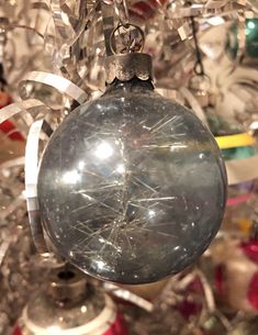 an ornament hanging from a christmas tree filled with glass balls and tinsel