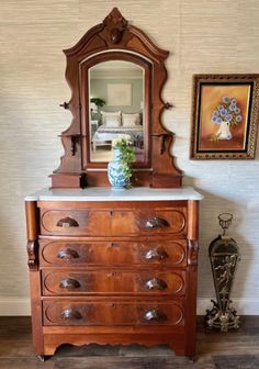 an old dresser with a mirror and vase on top