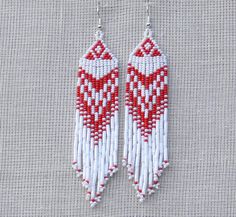 two red and white beaded earrings hanging on a hook with the word love written in it