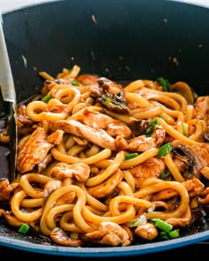 chicken and noodle stir fry in a skillet with a fork on the side