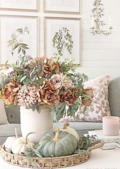 a white vase filled with lots of flowers on top of a table next to a couch