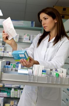 a woman in a white lab coat is holding some medicine