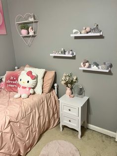 a hello kitty themed bedroom with pink and gray decor, shelvings and shelves on the wall