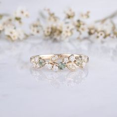 a close up of a ring on a white surface with flowers in the back ground