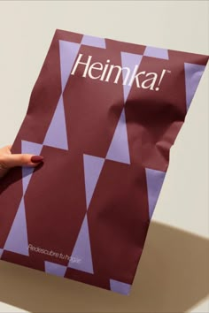 a person holding a bag with the word heinka on it in front of a white background