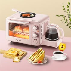 a pink toaster oven sitting on top of a counter next to bread and coffee