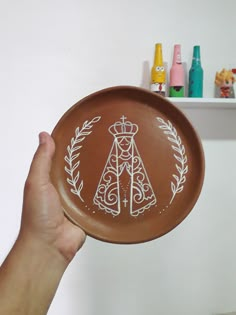 a person holding up a brown plate with white designs on the front and back of it