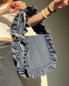 a woman holding onto a blue purse with ruffles on it