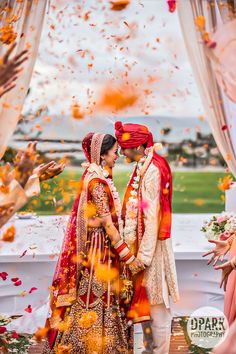 the newly married couple is surrounded by petals and confetti as they stand under an arch