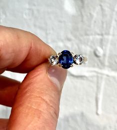 Lab grown sapphire and white spinel 9ct solid gold trilogy ring. This blue stone does test as sapphire, but I think it's more likely to be lab grown, but looks absolutely amazing. CONGRATS: Excellent  CENTRE STONE SIZE: 8mm x 6mm ( 1.8 carat ) CURRENT FINGER SIZE: UK size L. Can be altered to the sizes on the drop down menu. WEIGHT: 2.7g This ring has been professionally checked, cleaned and polished. Comes in a new box. Timeless Hallmarked Sapphire Ring, Classic Three Stone Jewelry With Lab-created Sapphire, Fine Jewelry Three Stone Lab-created Sapphire Ring, Sapphire Three Stone Sterling Silver Ring, Three Stone Sapphire Ring In Sterling Silver, Sapphire Three Stone Round Cut Diamond Ring, Three Stone Sapphire Diamond Ring With Round Cut, Fine Jewelry Sapphire Three Stone, Timeless Three Stone Blue Jewelry