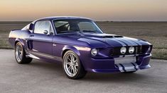 a purple mustang sitting on top of a parking lot next to an open field with grass