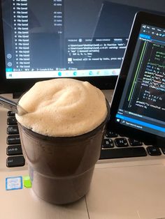 a cup of coffee sitting on top of a laptop computer