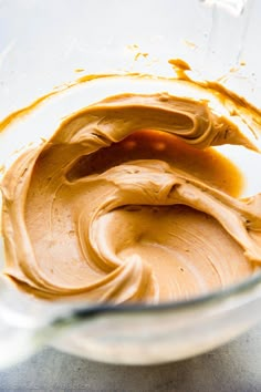 a glass bowl filled with peanut butter on top of a counter