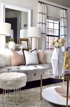 a living room filled with white furniture and lots of pillows on top of the couch