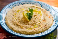 hummus with lemon and parsley on a blue and white plate