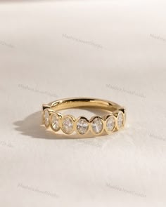 a yellow gold ring with five diamonds on it's side, sitting on a white surface