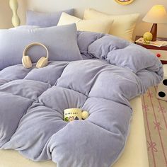 a purple comforter with headphones on it is in the middle of a bed